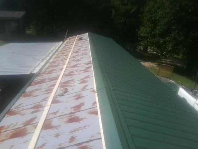 Old rusted panels beside newly installed green metal roofing — Wind Damage Roof Repair by Roofing Brothers in Canova