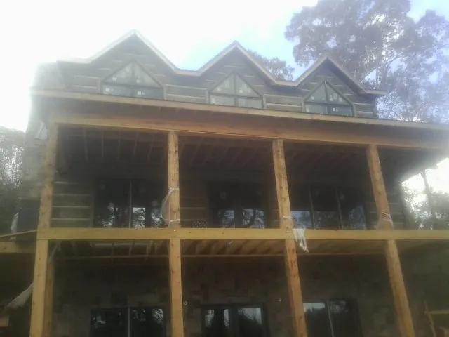 Dormers and porch framing on a large log home under construction — Roof Coating work by our crew in Canova