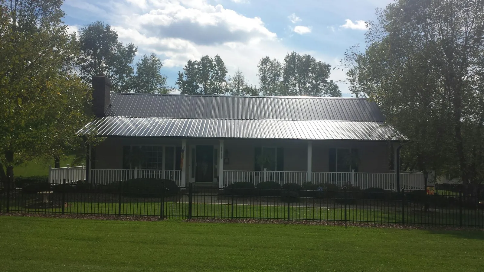 Gray metal roof on a brick ranch with a full width front porch — Gutter Guard Installation work by our crew in Canova