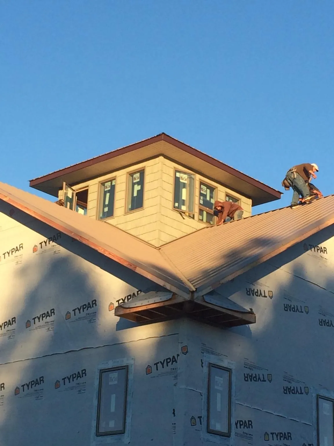 Roofers working around a rooftop cupola on a new metal roof at sunset — Roof Waterproofing in Canova by Roofing Brothers